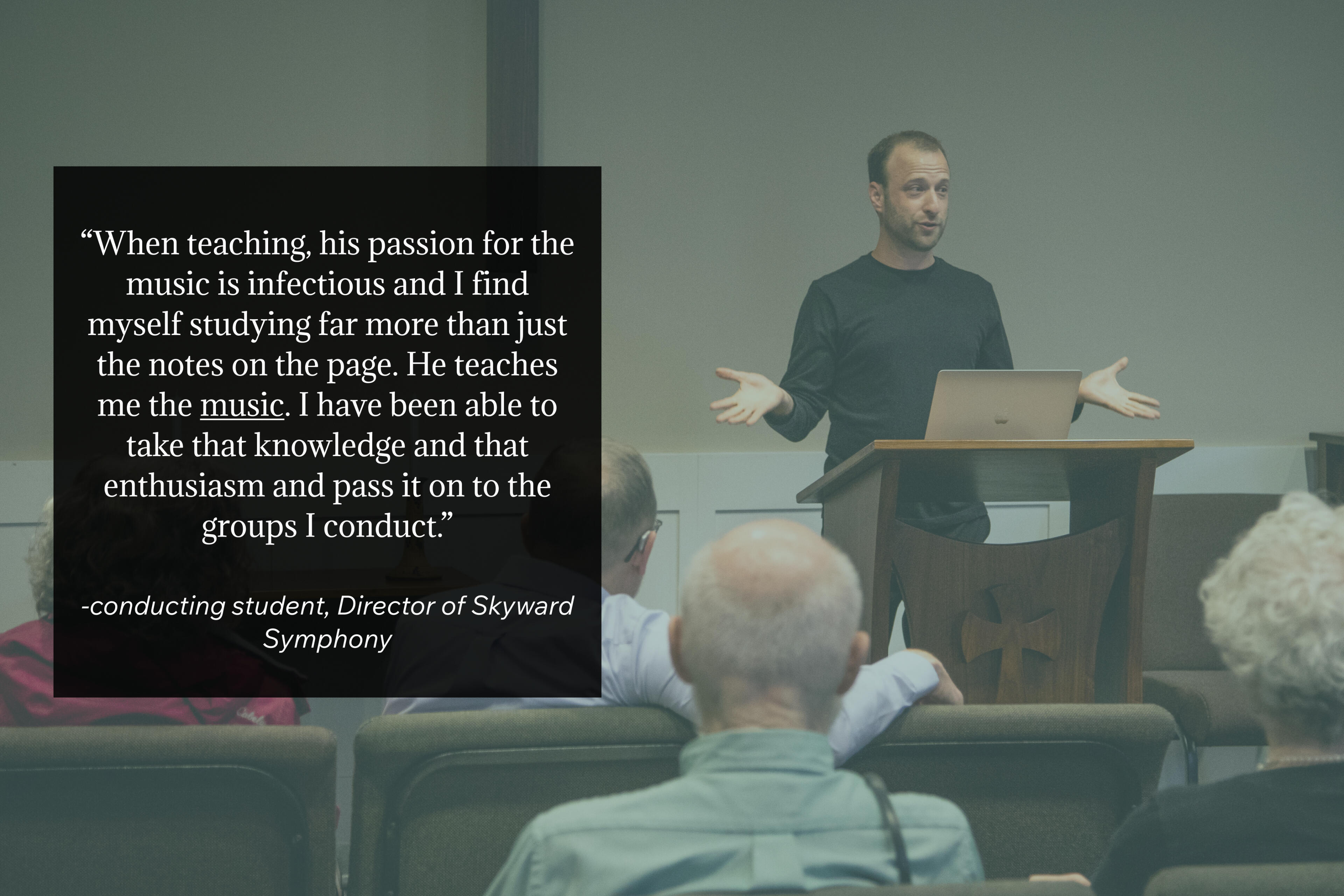 Dr. Matthew Mainella stands behind a wooden lectern with a laptop open in front of him. His hands are spread wide, his face is engaged - he appears to be talking about something he is excited about. The foreground has a quote from his conducting student.